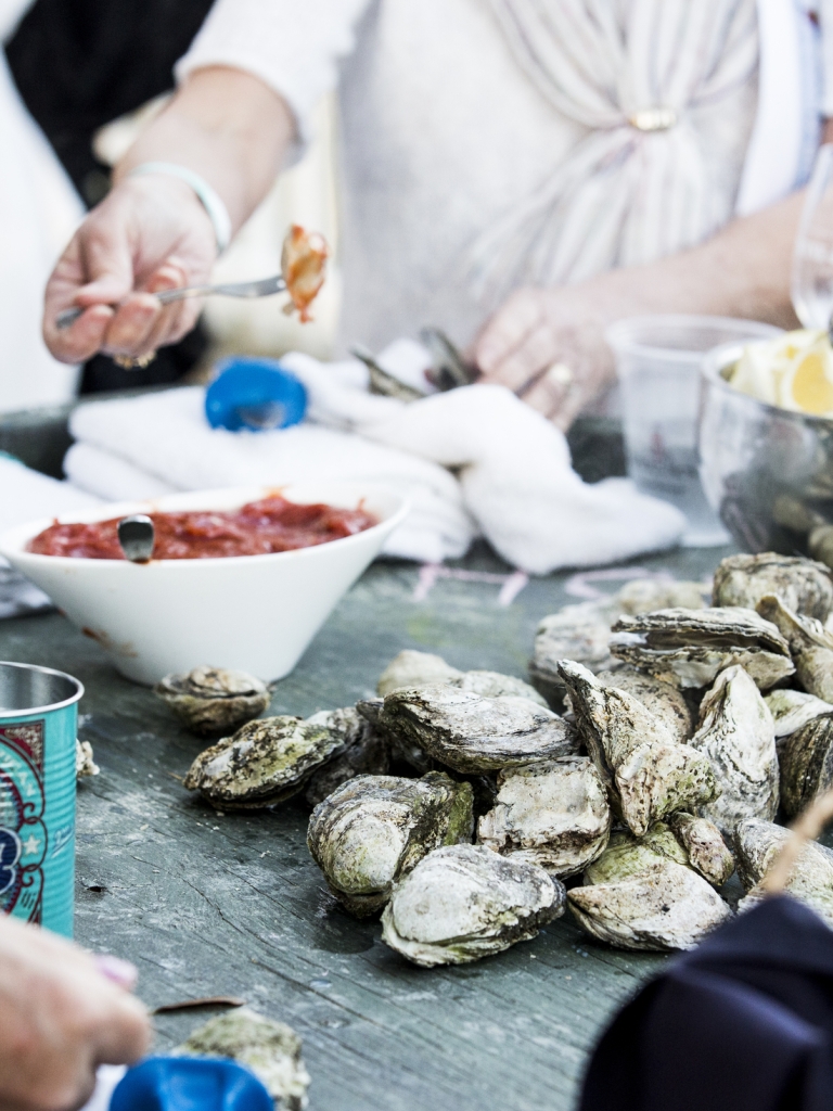 Group of people gathering around many oysters 