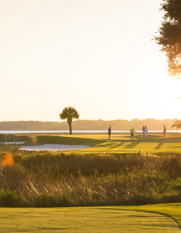 A group of golfers on the course at sunset 