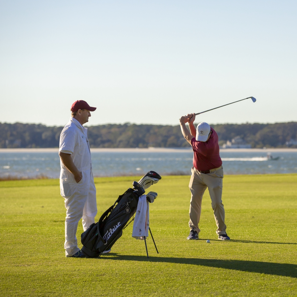 Two men golfing with the ocean in the background 